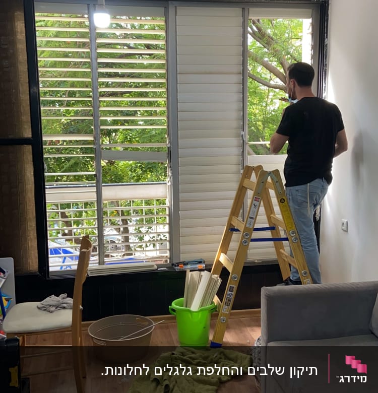 אדם מתקין תריסים בחלון עם סולם